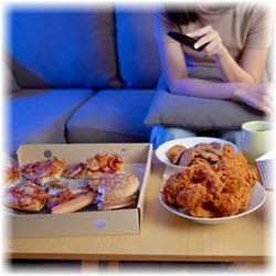 Photo of a box of pizza, fried chicken and cookies on a living room table