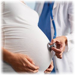 Photo of a doctor with a stethoscope on the pregnant belly of a woman