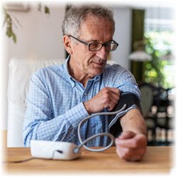 Photo of a man taking a blood pressure reading on a machine at a table