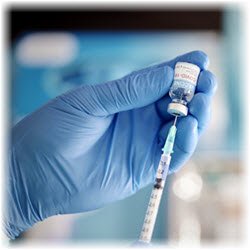 Photo of a needle and vaccine vial in a gloved hand