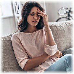 Photo of a woman on her couch with a headache