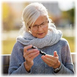 Photo of a senior woman sitting outdoors measuring her blood sugar level