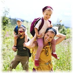 Photo of a young family hiking through a field on a sunny day