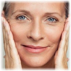 Photo of a smiling woman with her hands on the sides of her face