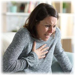 Phot of a panicked woman clutching her chest at home