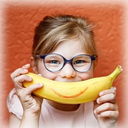 Photo of kid holding a banana with a smile 