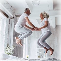 Photo of couple enjoying jumping on the bed together