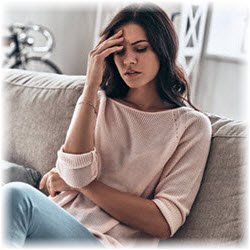 Photo of a woman on her couch with a headache