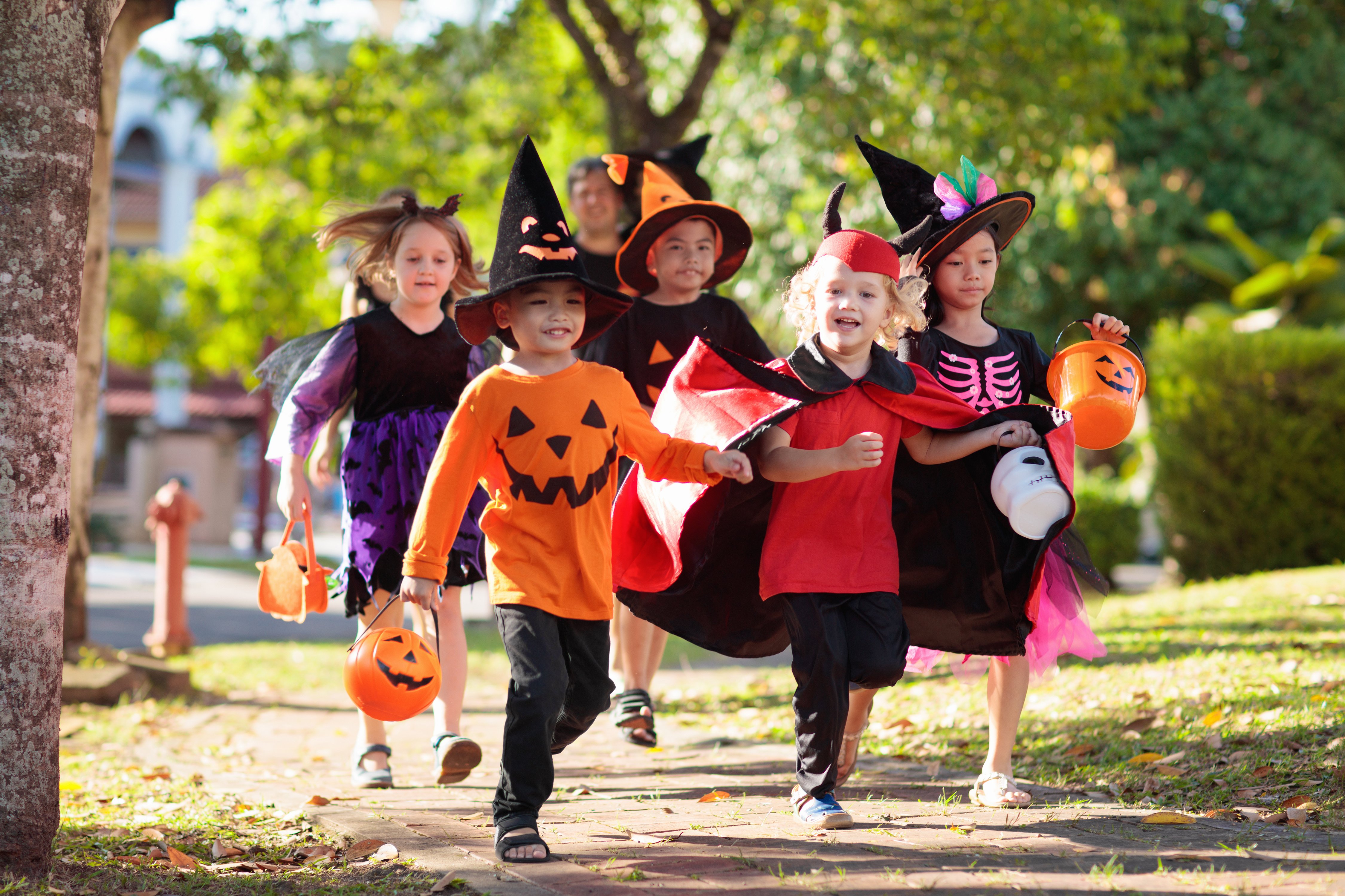 Photo of a group of happy children dressed up in their halloween costumes, trick or treating