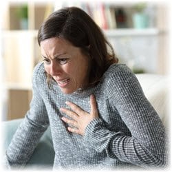 Phot of a panicked woman clutching her chest at home