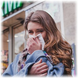 Photo of a woman blowing her nose outside while wearing multiple layers of clothing