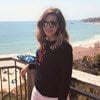 Photo of Sara posing on a balcony overseeing the beach on a sunny day