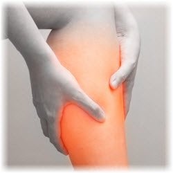 Black and white photo of a person holding their calf which is highlighted orange to indicate pain