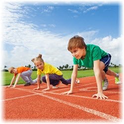 Three young children getting ready at a racetrack starting line